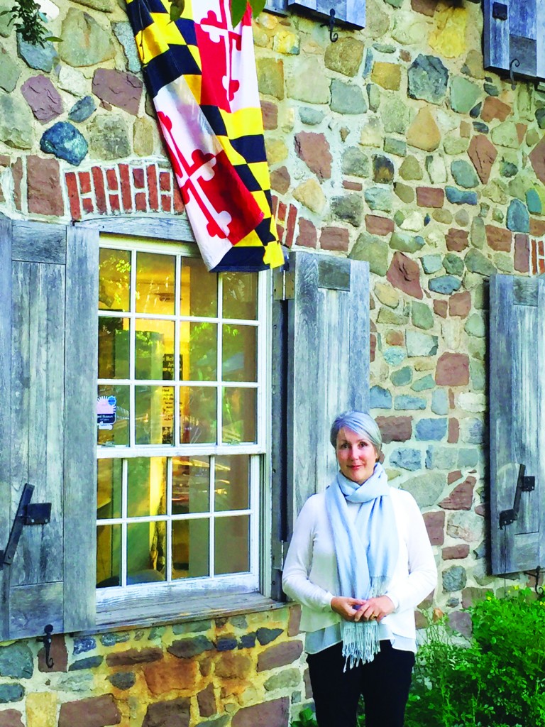 Maier in front of the Old Stone House, which proudly displays a Maryland flag. Credit: Mirielle Clifford